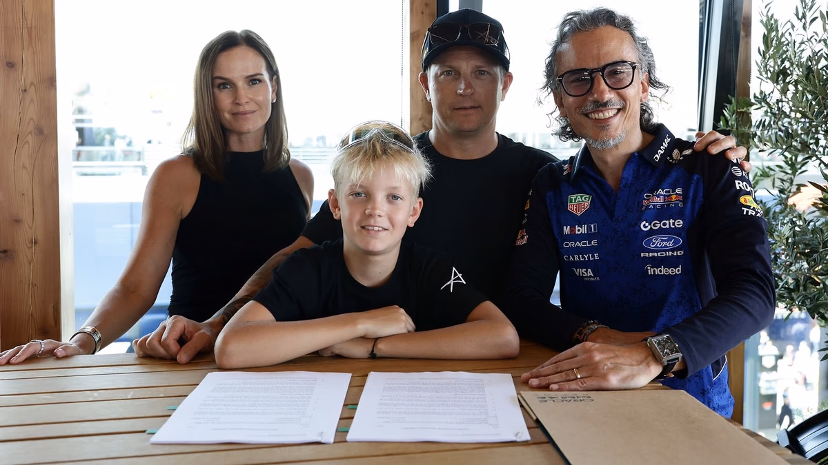 Robin Räikkönen, de 11 anos, sentado à mesa com o contrato assinado, ao lado da mãe Minttu, do pai Kimi Räikkönen e do chefe da Red Bull, Laurent Mekies